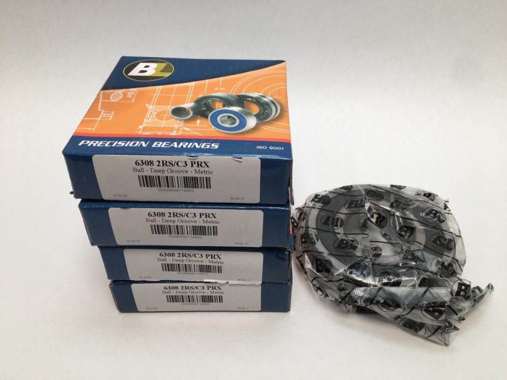 Four stacked boxes of BL 6308 2RS/C3 deep groove ball bearings beside bearings wrapped in plastic