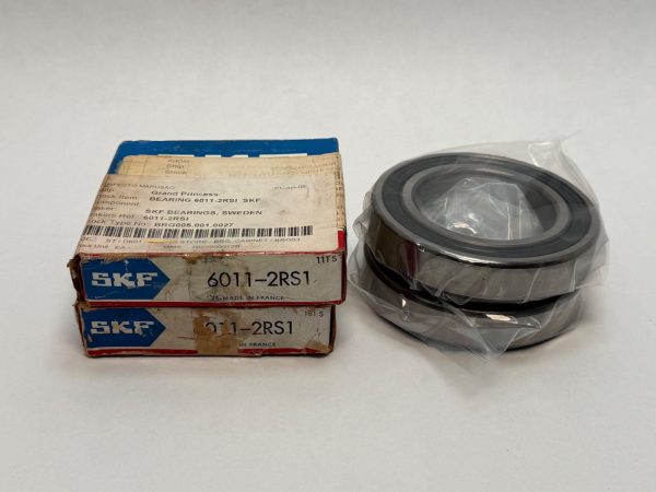 Two SKF 6011-2RS1 rubber-sealed bearings stacked in plastic wrap next to their original boxes
