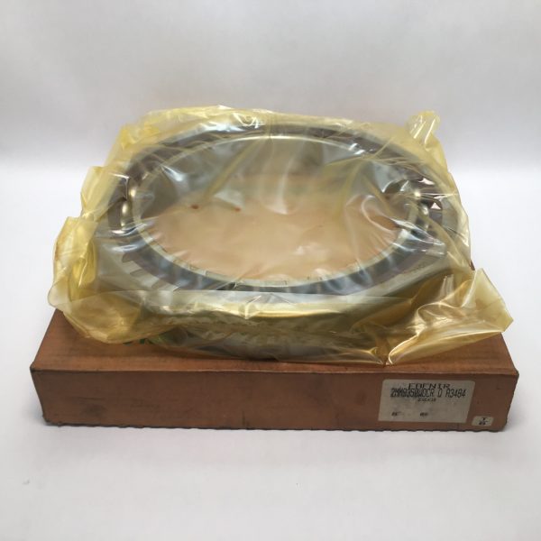 Large angular contact ball bearing wrapped in yellow plastic, resting on cardboard box
