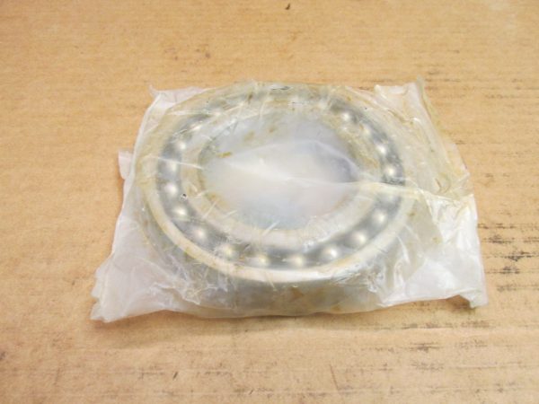 NTN 1216K self-aligning ball bearing wrapped in plastic, resting on a wooden surface