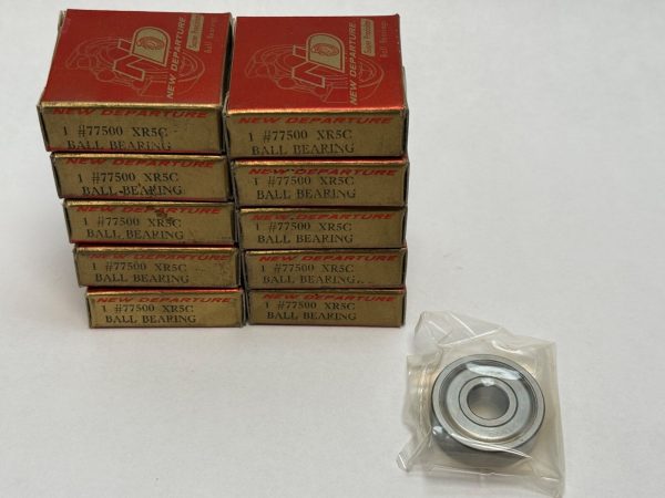 Ten stacked boxes of New Departure #77500 XR5C ball bearings beside one unpackaged metal sealed bearing