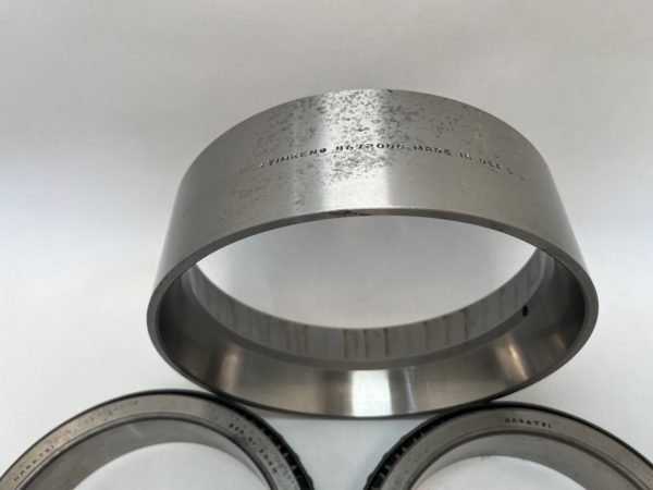 Timken 46720DC double bearing cup, metal ring stamped with part number, shown above two tapered roller bearing cones