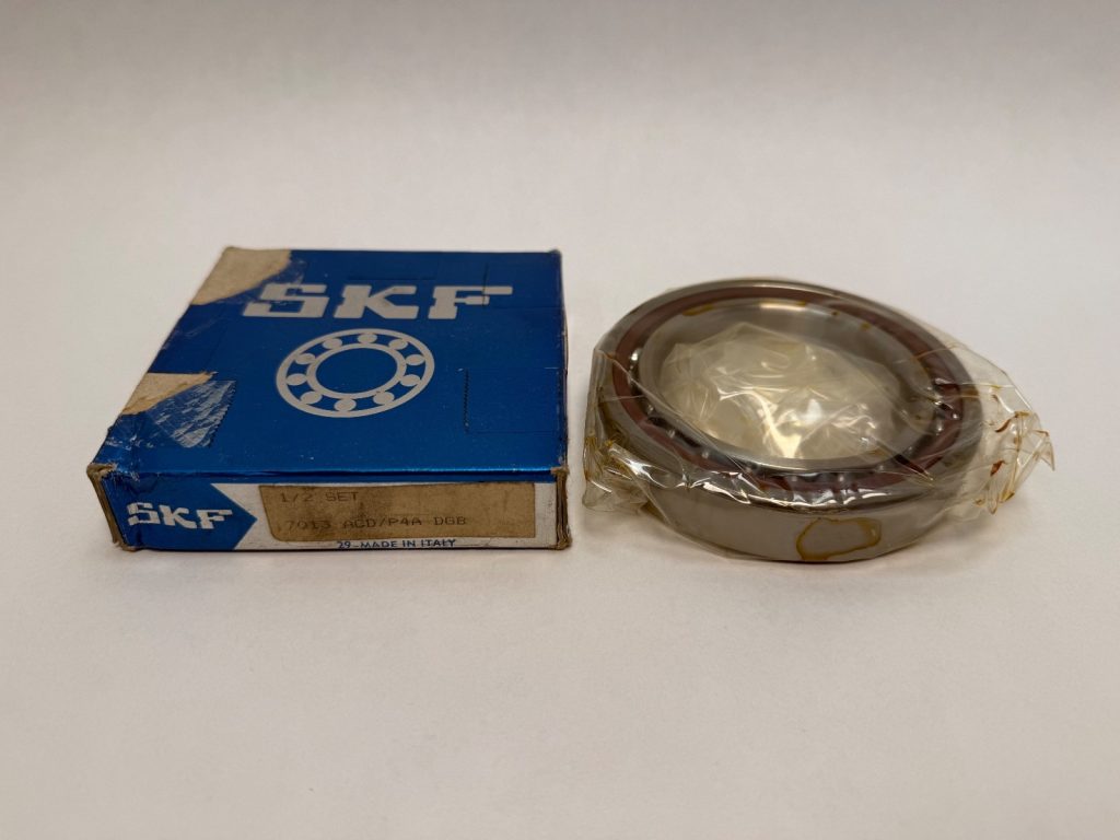 SKF 7013 ACD/P4A angular contact ball bearing, wrapped in plastic, next to its original SKF box