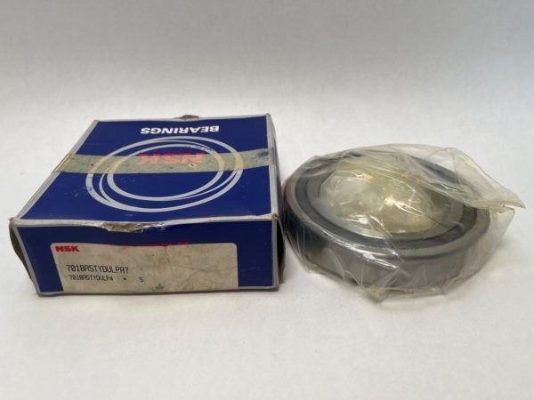 NSK 7018A5TYDULPA7 angular contact ball bearing, shrink-wrapped, beside its labeled NSK bearings box
