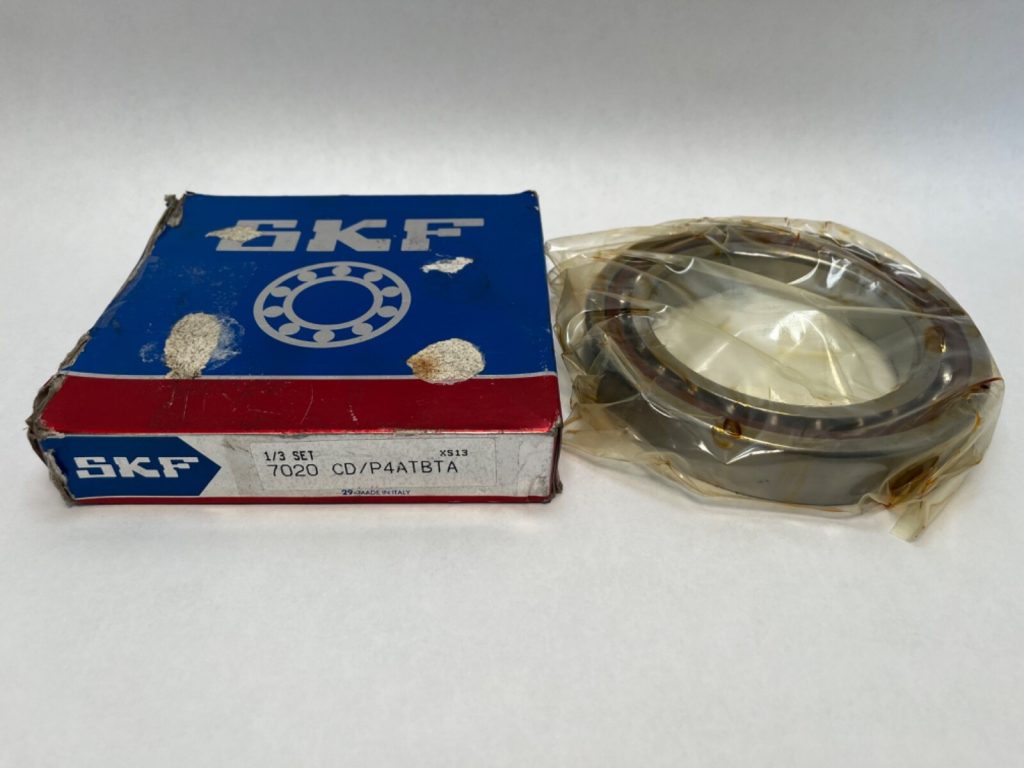 SKF 7020 CD/P4ADGA angular contact ball bearing, shrink-wrapped, beside its original SKF box