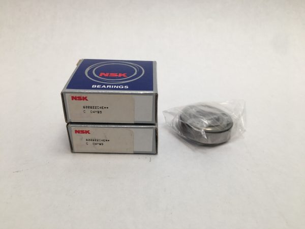 Two NSK deep groove ball bearing boxes next to one bearing in plastic wrap