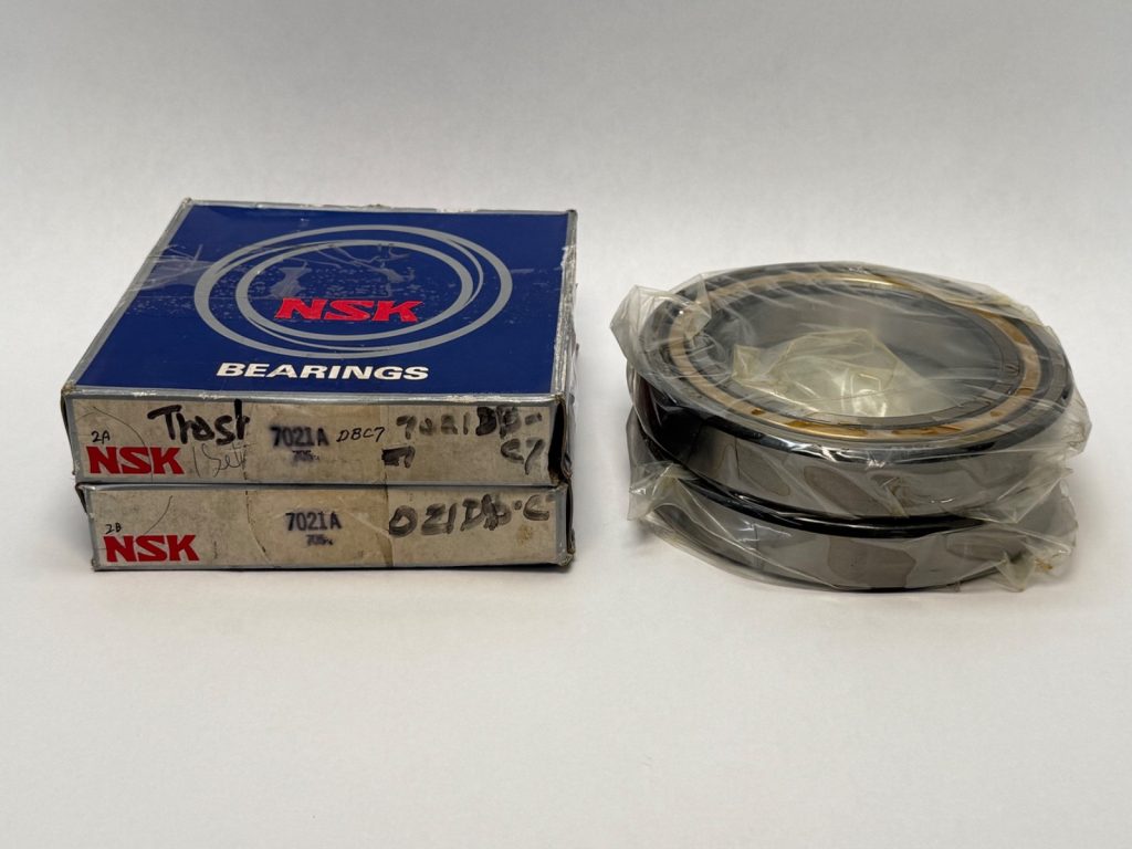 Two NSK 7021A angular contact ball bearings, shrink-wrapped, next to their original NSK boxes