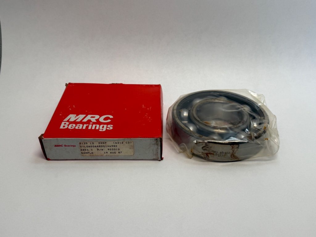 MRC 312S deep groove ball bearing, open, shown in plastic wrap beside its red MRC Bearings box